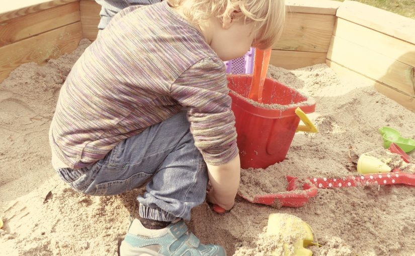 Spielender kleiner Junge im Sandkasten